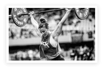 A woman lifting a barbell in front of a crowd.