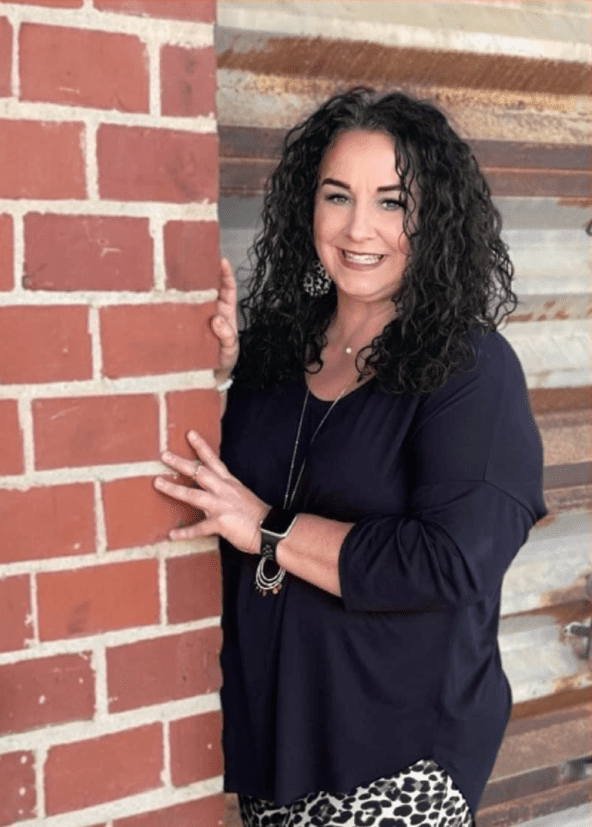 A woman standing next to a brick wall.