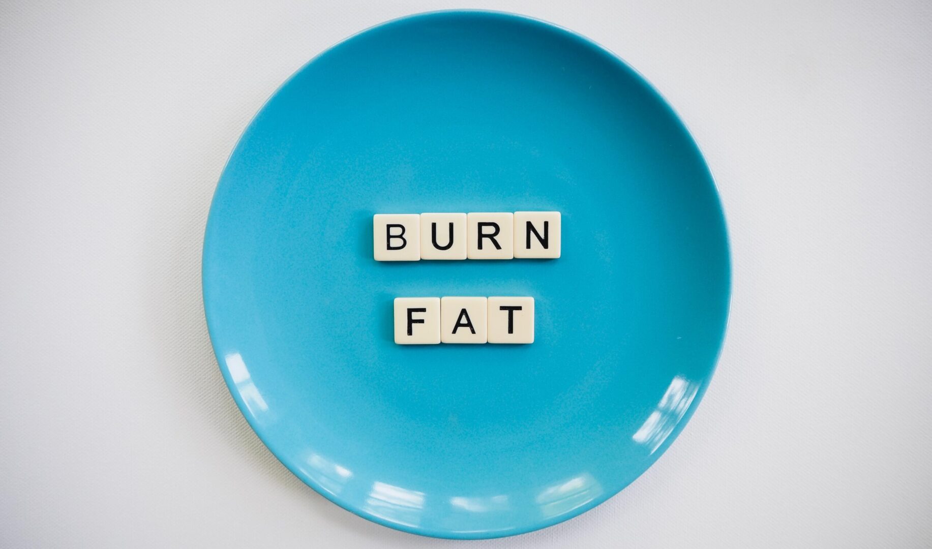 A blue plate with the words burn fat spelled out in scrabble tiles.