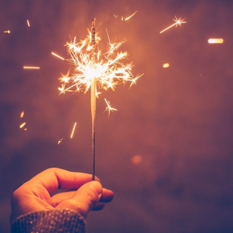 A person holding sparklers in their hand.