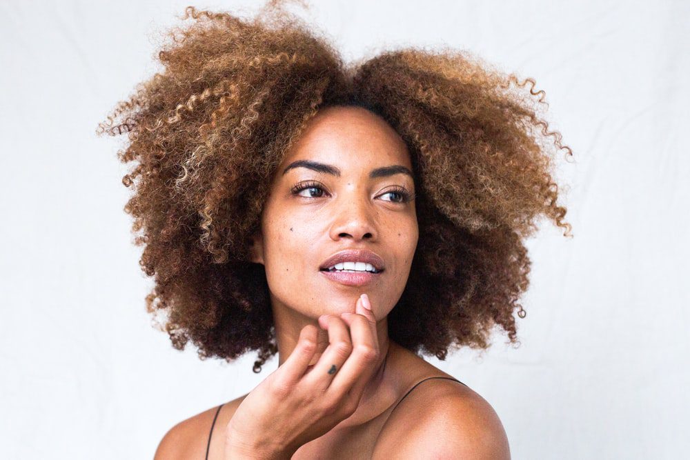 A woman with curly hair is posing for the camera.