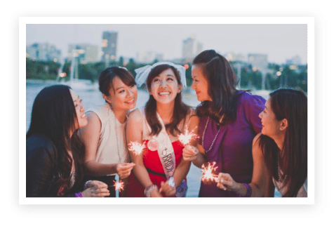 A group of women standing around each other holding sparklers.